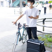 自転車配達員がスマホで次の配達先を確認の写真