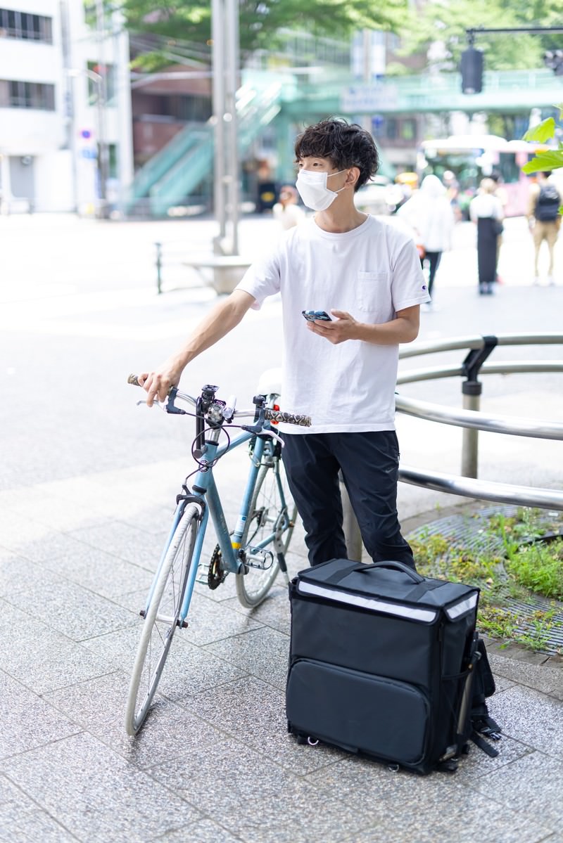 自転車配達員がスマホで配達先を確認［モデル：TSURUTAMA］