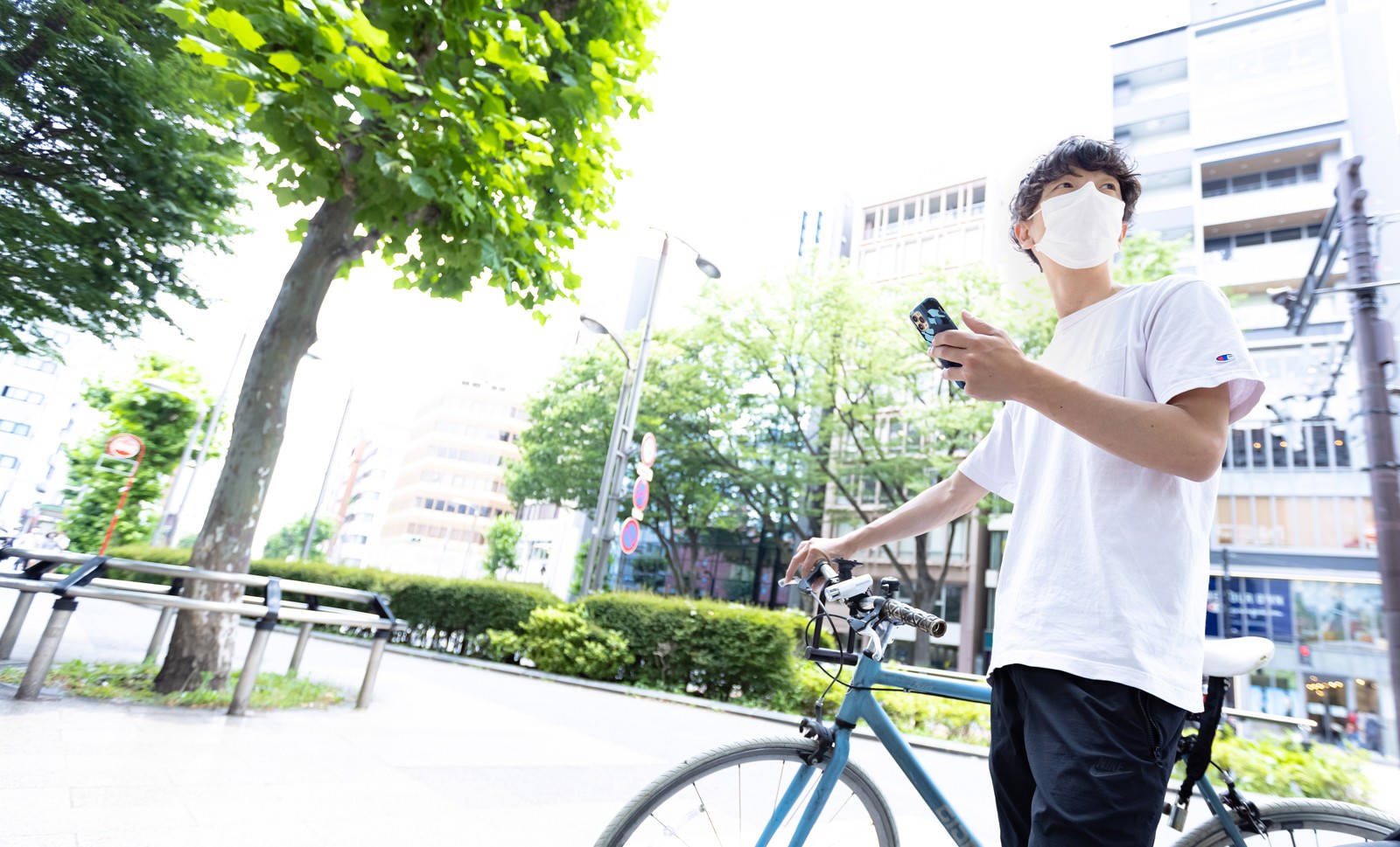 スマートフォンでマップアプリを見ながら配達先を確認する白いシャツの男性配達員［モデル：TSURUTAMA］