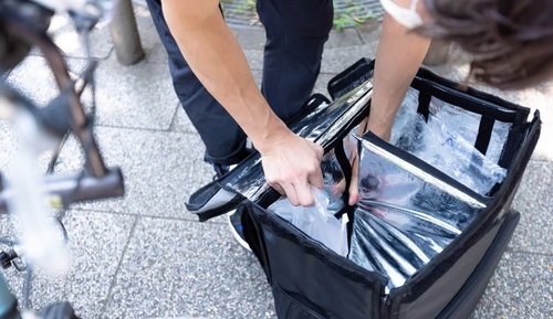 預かった商品を専用の四角い保温バッグに詰め込む配達員