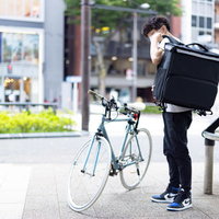 ウバッグを背負う男性配達パートナーと自転車の写真