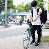 配達先の住所をスマートフォンで確認するフードデリバリーの男性の写真