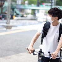 周囲環境を気にしながら自転車で配達するフードデリバリーの男性の写真