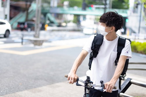 周囲環境を気にしながら自転車で配達するフードデリバリーの男性