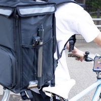 スマホの地図を見ながら配達地に向かう配達員の後ろ姿の写真