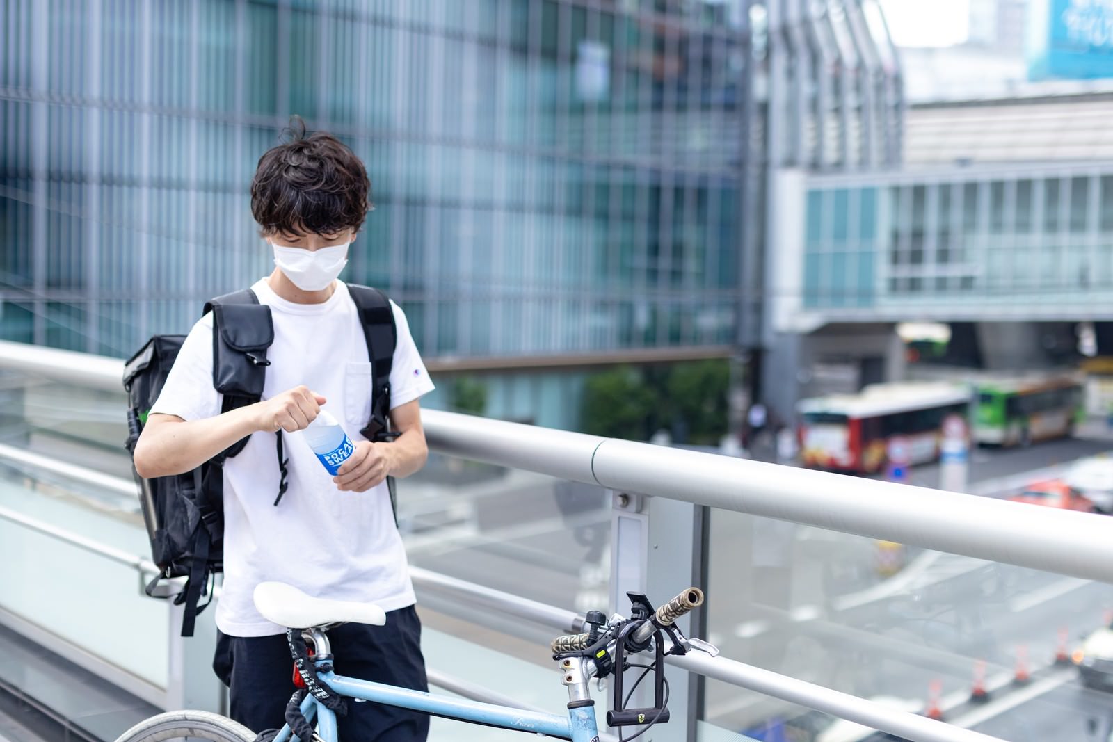 白いシャツを着た配達パートナーの男性が水筒で水分補給している様子［モデル：TSURUTAMA］