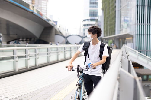 歩道橋を歩く配達パートナーと自転車を押す男性
