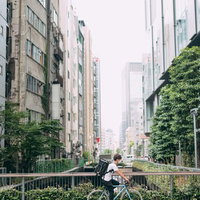 渋谷川沿いで自転車に乗って配達地に向かうフードデリバリー男性の写真
