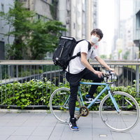 チャリで来た、フードデリバリーの配達員が自転車を押すの写真