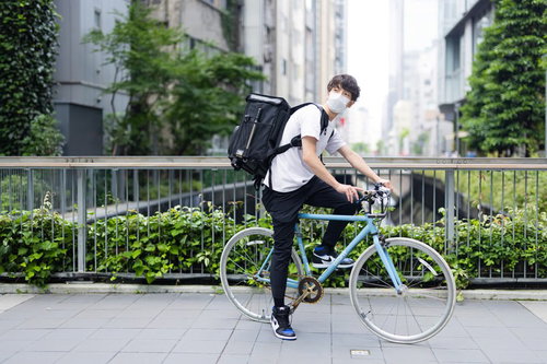 チャリで来た、フードデリバリーの配達員が自転車を押す