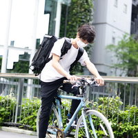 イケメンマスク姿の男性配達員が自転車で配達中の写真