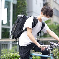 スマホでナビを確認しながら自転車で配達をする男性の写真