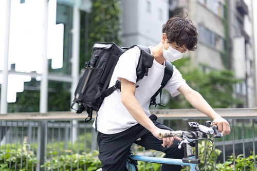 スマホでナビを確認しながら自転車で配達をする男性