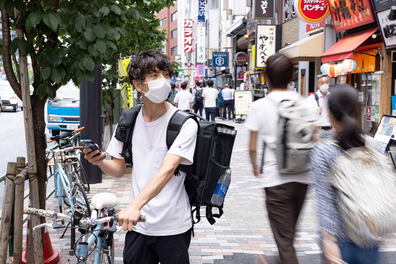 商品を受け取る店舗を探す男性配達員のフリー素材