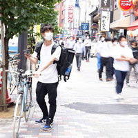 お昼時にフードデリバリーの配達依頼を受ける自転車配達員の男性の写真