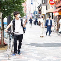 スマートフォンと地図でお店の場所を探すフードデリバリーの男性の写真