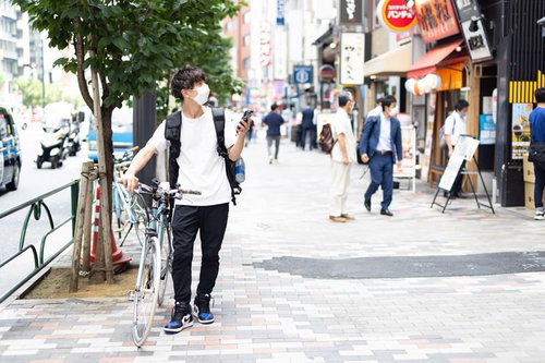 スマートフォンと地図でお店の場所を探すフードデリバリーの男性