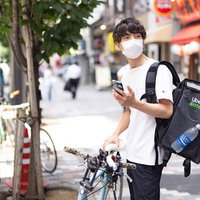 お昼時に見かけるフードデリバリーの配達員と自転車の写真