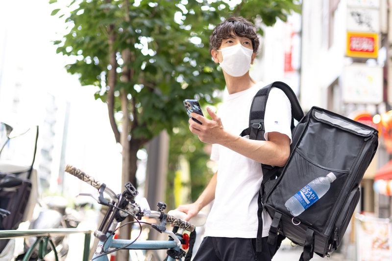 ゴーストレストランなので依頼先の店舗を探しても見当たらない様子の配達員のフリー素材