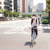 自転車に乗って配達場所に向かうフードデリバリーの男性の写真