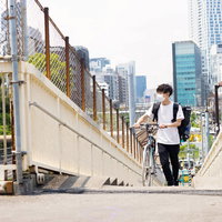 歩道橋の階段を歩くフードデリバリーの男性配達員の写真