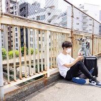 次の配達までの間、ベランダで休憩する配達員の男性の写真