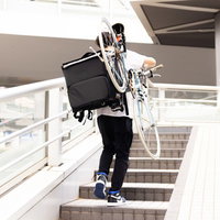 自転車を担いで階段を登る配達員の労働風景の写真