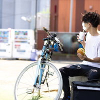 配達員が休憩中にハンバーガーを食べる（つまみ食い風）の写真