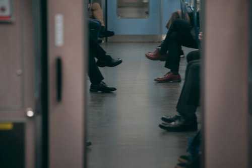 電車の座席に座った通勤中の足と靴、乗客の足元風景