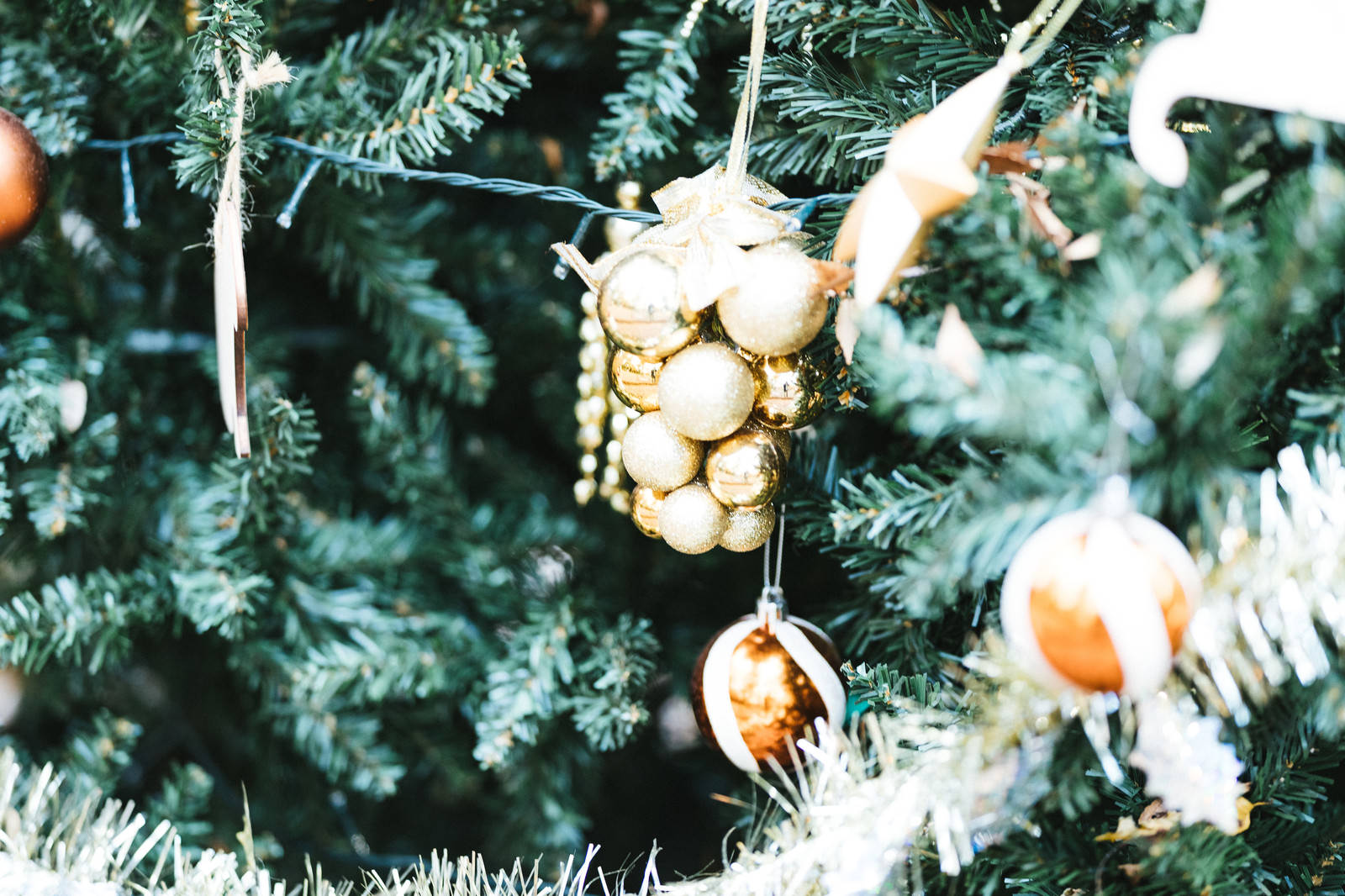モミの木の枝に吊り下がったゴールドのクリスマスオーナメントのクローズアップ