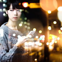 メールひとつで終わる5年。夜景の街でスマホを持つ女性の写真