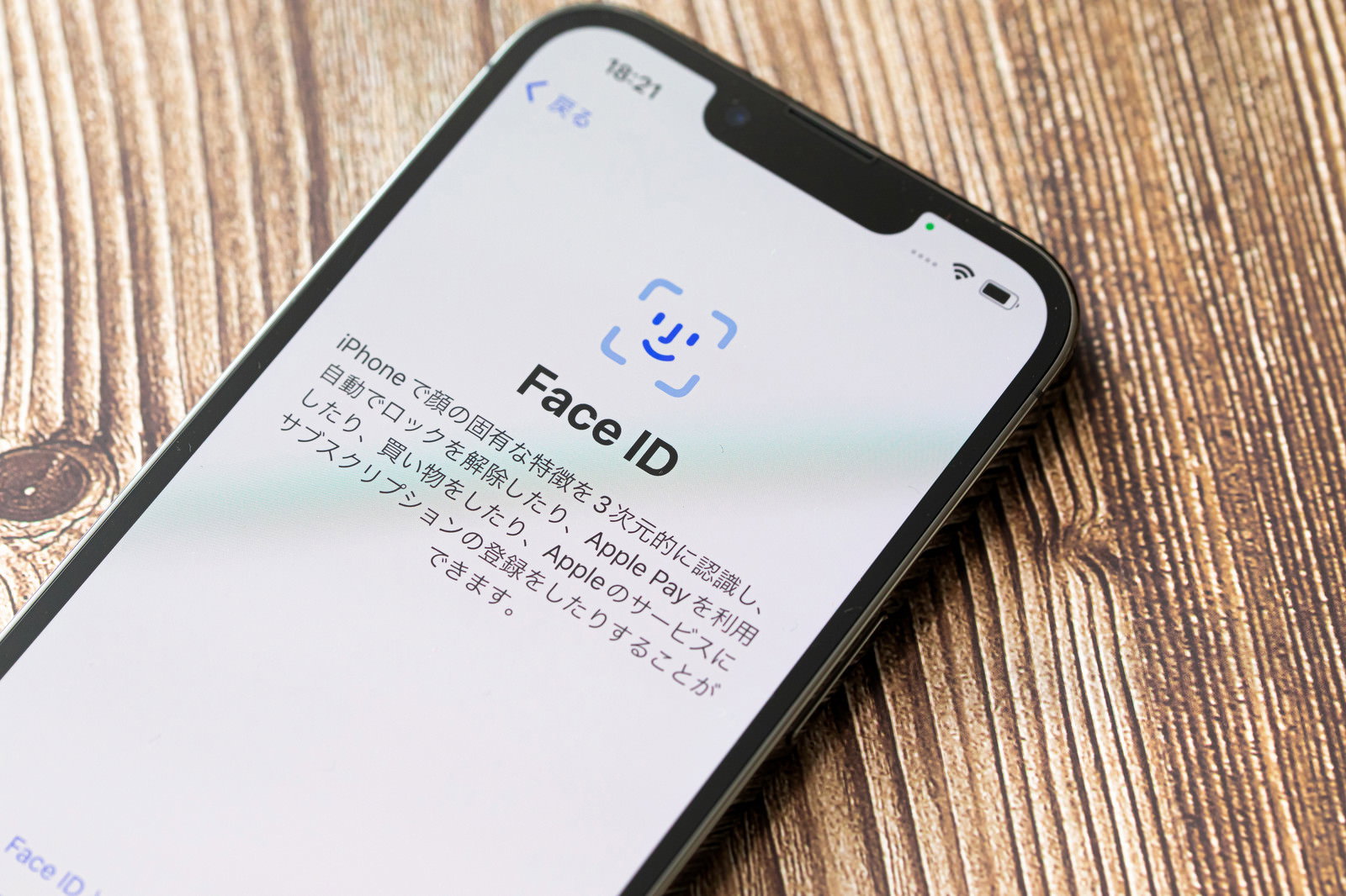 木目調の背景にFace IDの設定画面を表示するiPhone13が置かれている