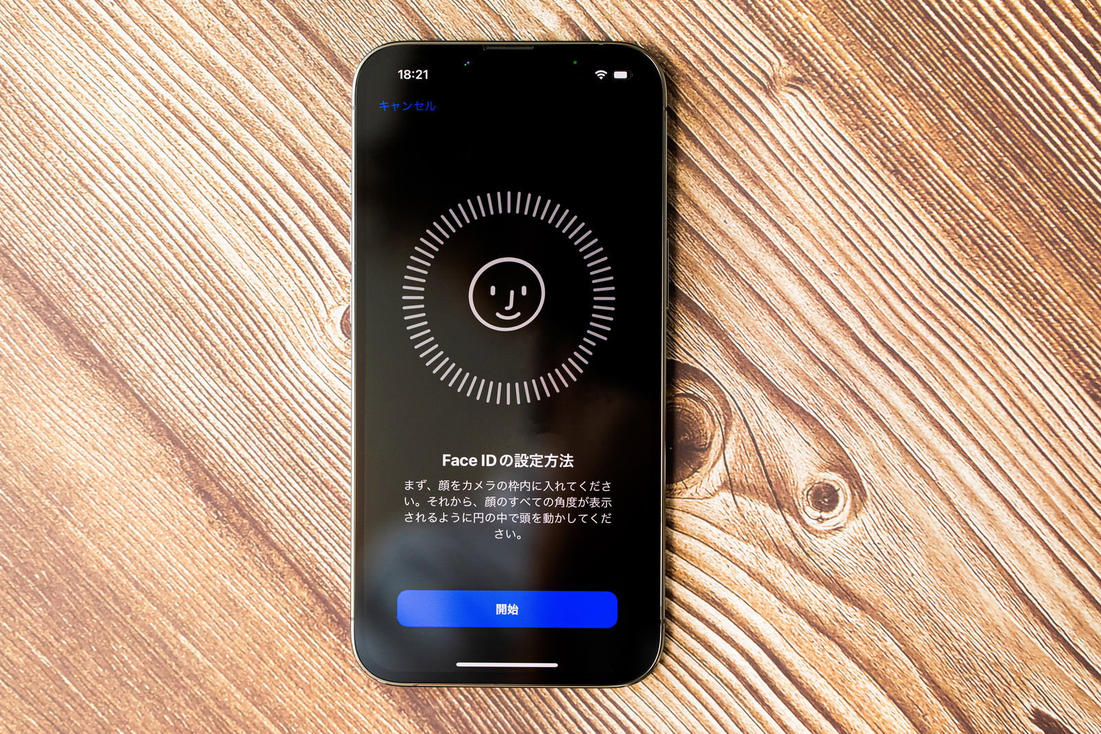 木目のテーブルに置かれたiPhoneにFaceID設定画面が表示されている