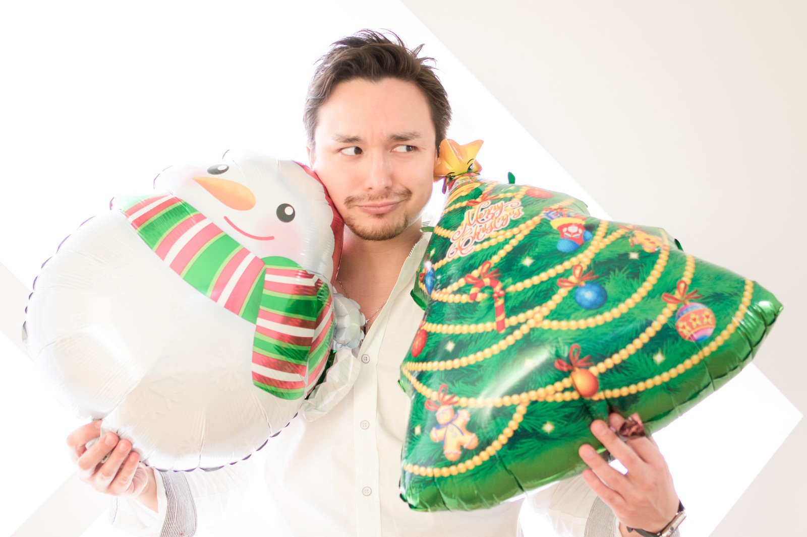クリスマス用バルーンを抱えた独身男性が少し寂しげな表情で横を向いている［モデル：Max_Ezaki］