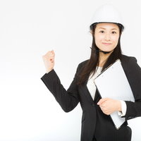 現場で作業を行うOL女性のガッツポーズ、建設現場での活躍の写真