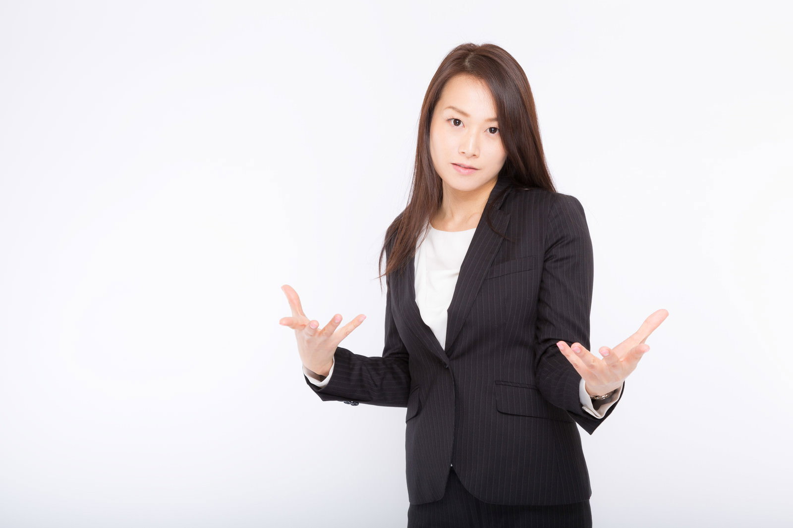黒いスーツを着た女性が白背景で両手を左右に広げてプレゼンしている様子［モデル：土本寛子］