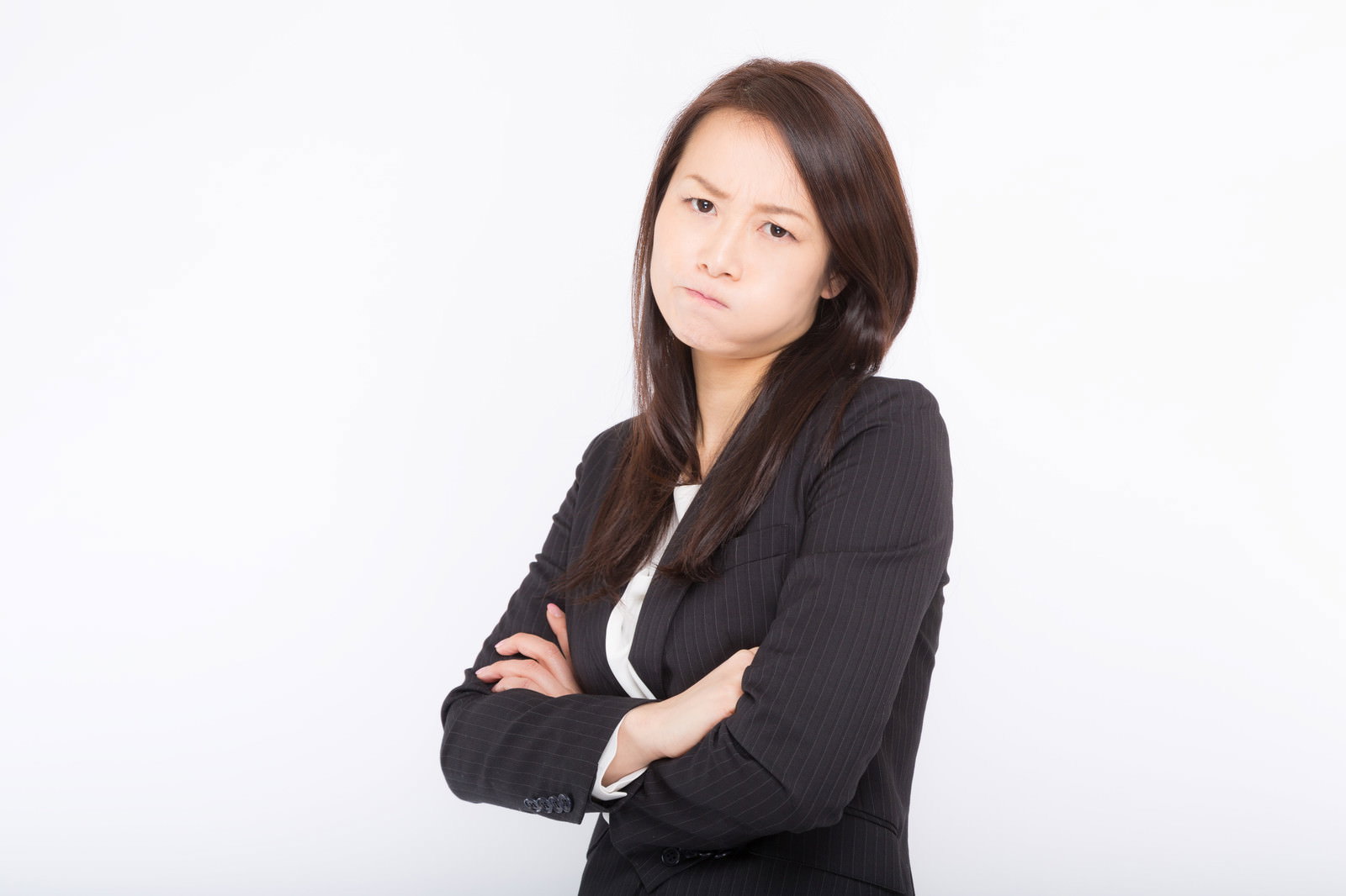 黒いスーツを着た女性が腕を組んで怒った表情をしている［モデル：土本寛子］