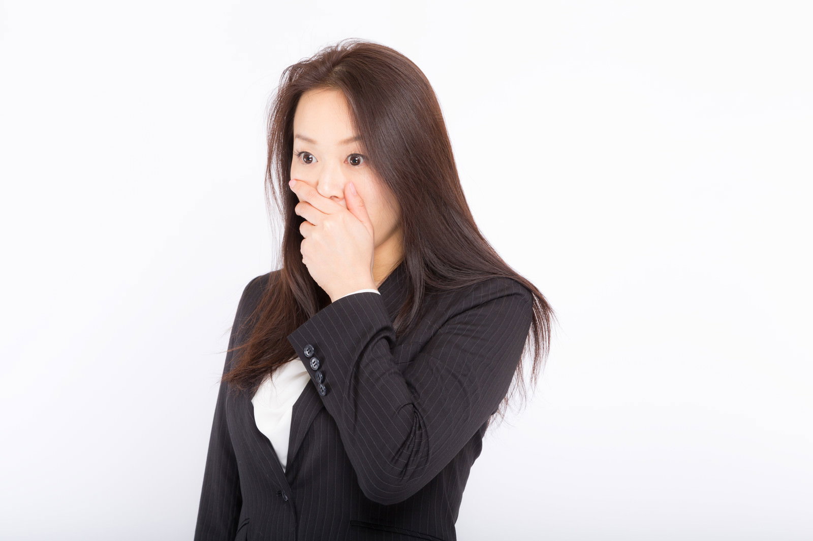黒いスーツを着て片手で口元を覆っている女性社員［モデル：土本寛子］
