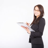 スーツ姿で棚卸し項目にチェックをつける女性の写真