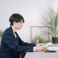 書類を見ながらペンを走らせるビジネスパーソンの写真