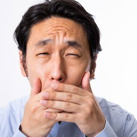 思わず口を抑えて目を細めてしまう男性のあくびと絶句の写真