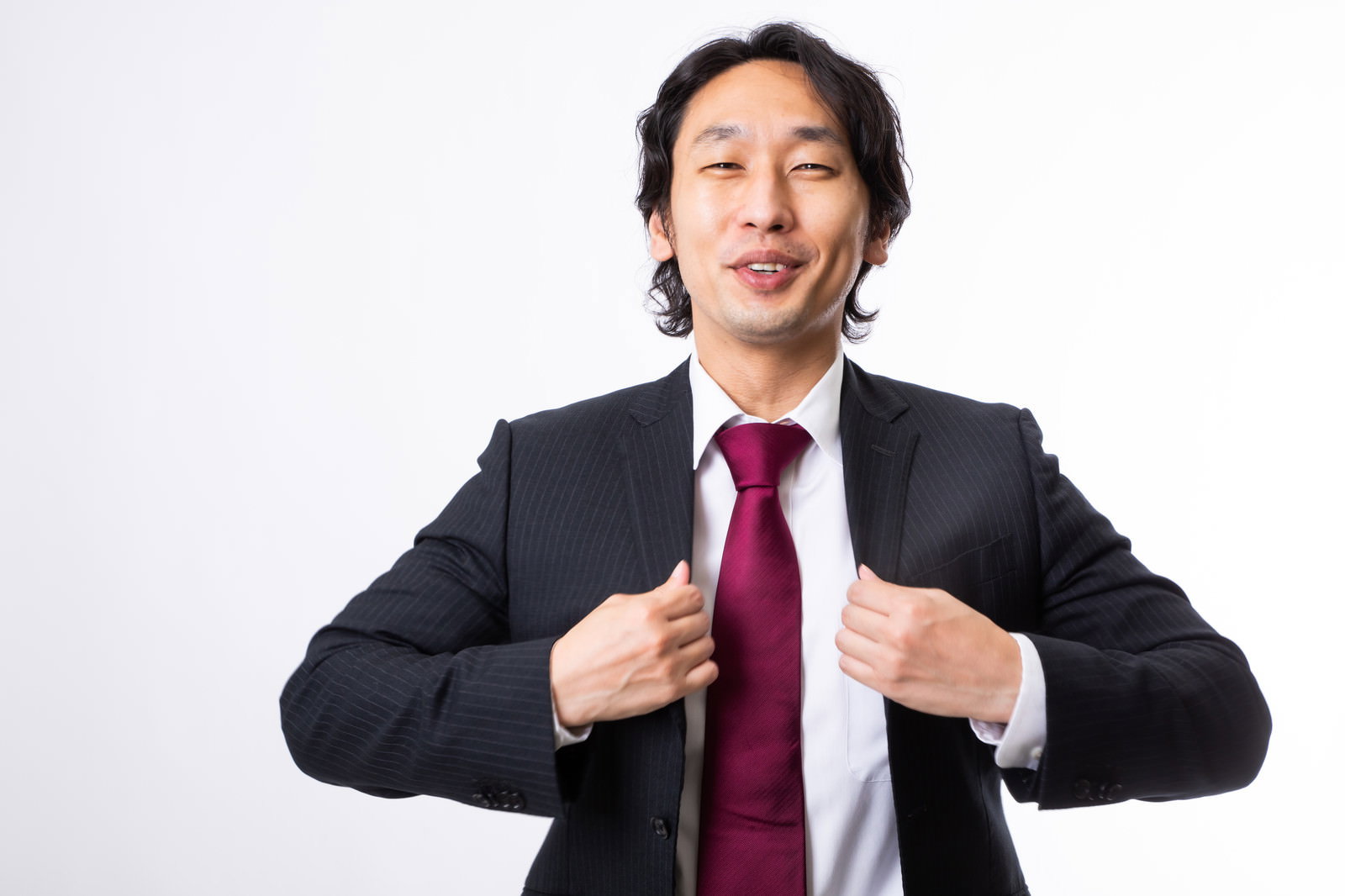 赤いネクタイのスーツ姿でガッツポーズを決める笑顔の男性［モデル：大川竜弥］