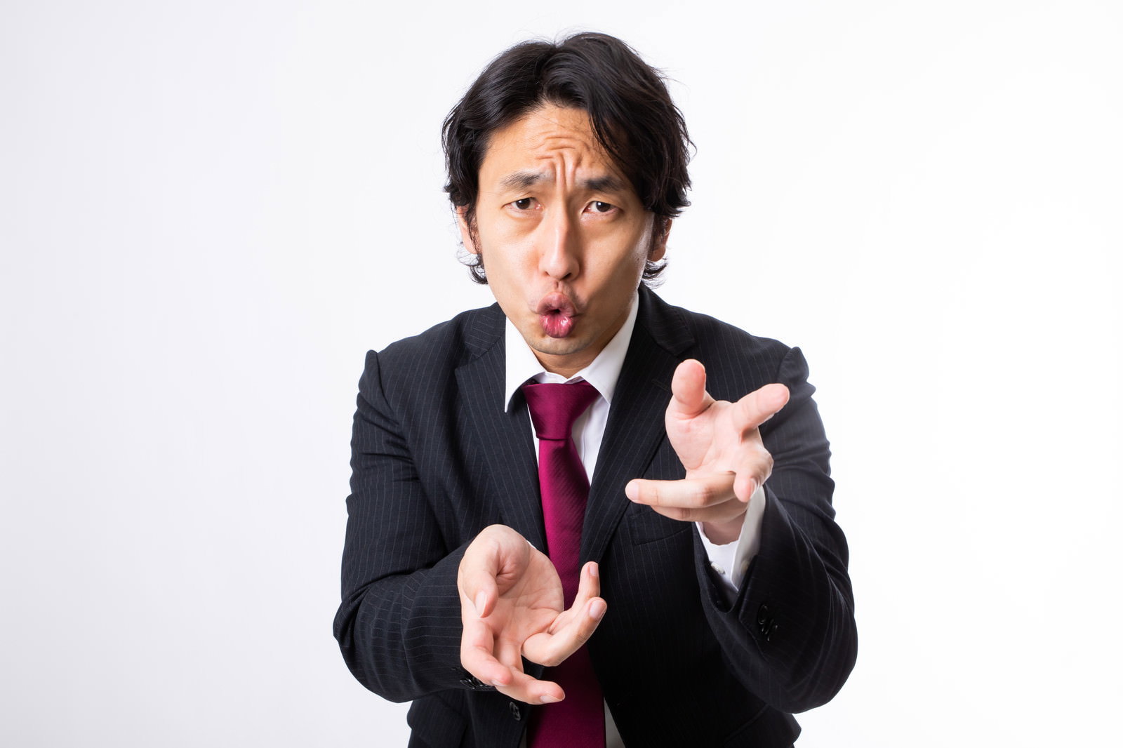 スーツ姿の男性が両手を前に出して熱心にプレゼンテーションしている様子［モデル：大川竜弥］
