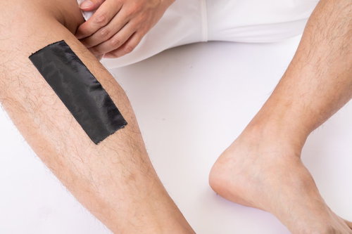 脱毛シートを毛深い足のすね毛に貼る男性のメンズ美容ケア