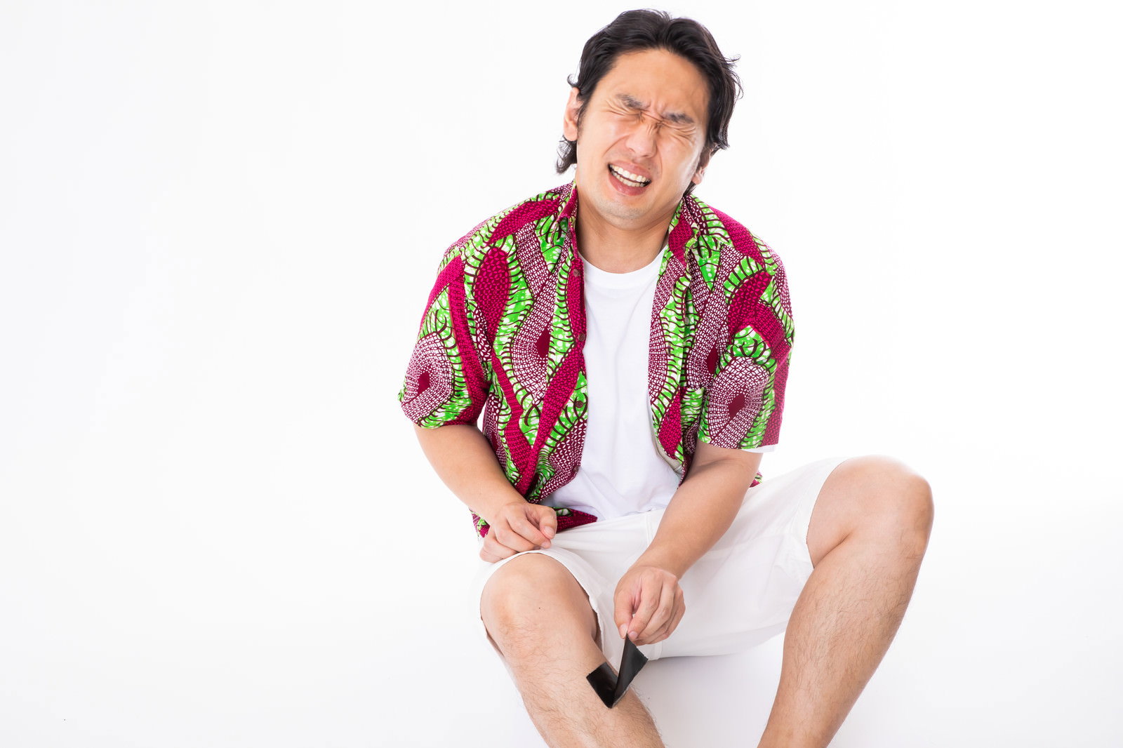 脱毛シートを剥がして痛がる表情を見せる男性［モデル：大川竜弥］