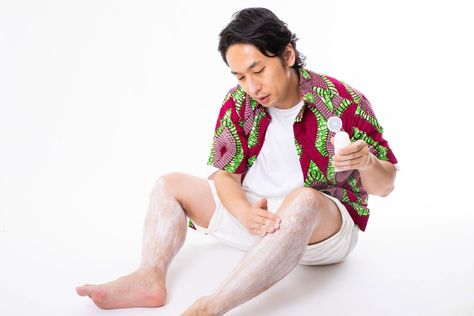 除毛クリームを手に取り毛深いすね毛に塗り込んでいる男性［モデル：大川竜弥］