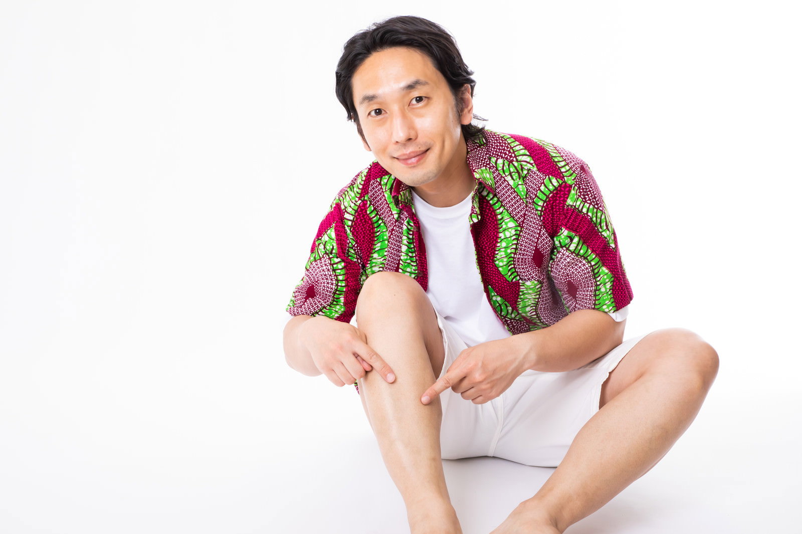 剃毛したすねを指差して笑顔を向けるチェックシャツ姿の男性［モデル：大川竜弥］