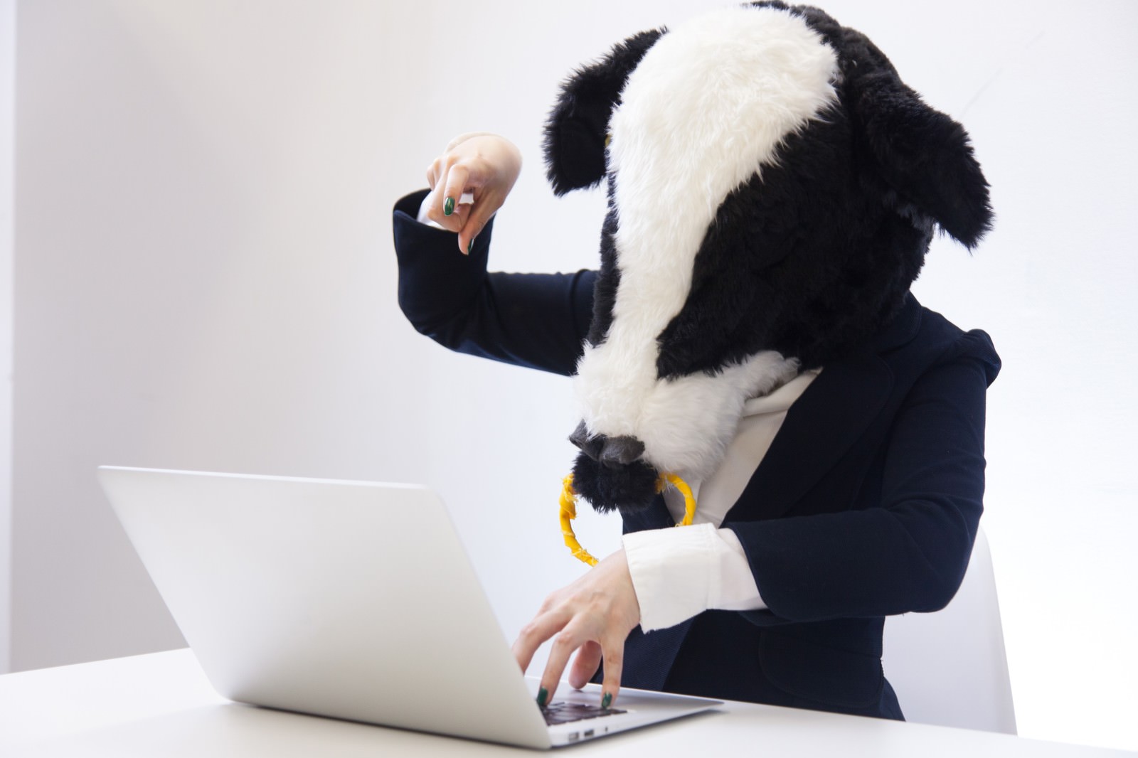 ノートパソコンでタイピングするエト牛のキャラクター。紺色のスーツ姿で、両手を使って入力作業をしている［モデル：古性のっち］