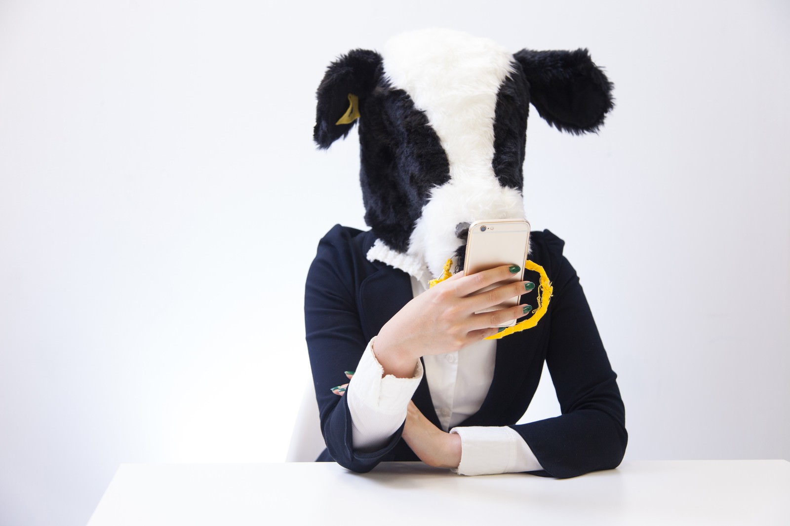 エト牛の被り物姿でスマートフォンを見る人物［モデル：古性のっち］