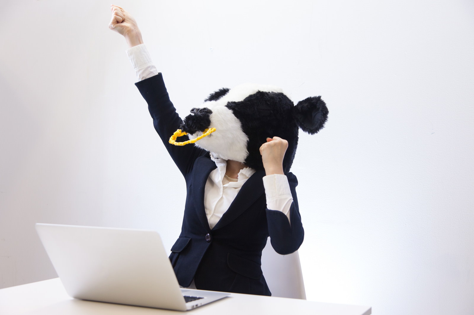 ビジネススーツを着た牛のキャラクターが両手を上げてガッツポーズをしている［モデル：古性のっち］